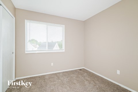 the bedroom of a home with a window and carpet