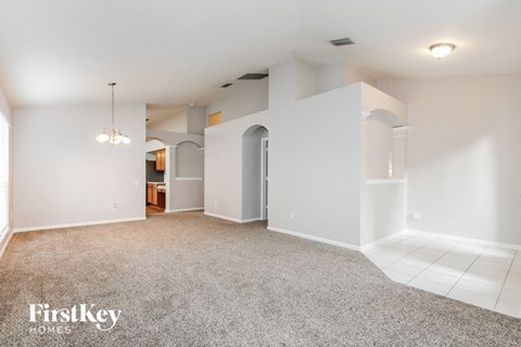 a spacious living room with carpet and white walls