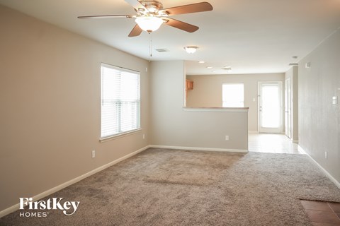a empty living room with a ceiling fan and a carpet