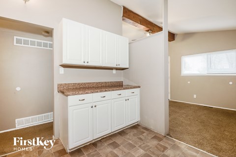 A kitchen area with white cabinets and a countertop.