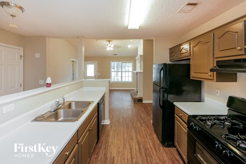 A kitchen with wooden floors and a black refrigerator.