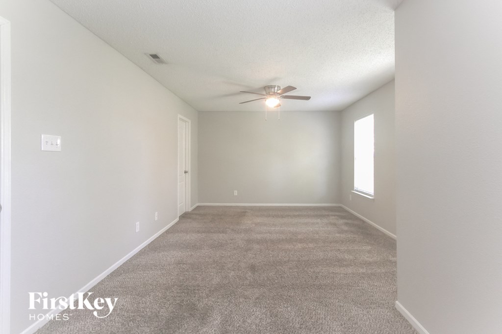A spacious room with a carpeted floor and a ceiling fan.
