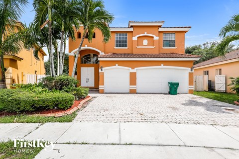 a orange house with white garage doors and palm trees