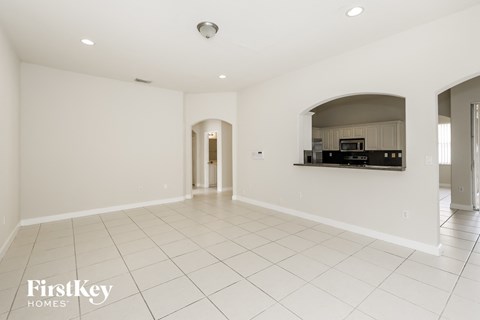 an empty kitchen and living room with white tile floors and white walls