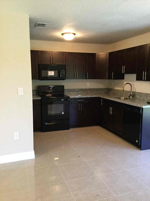A kitchen with black appliances and brown cabinets.