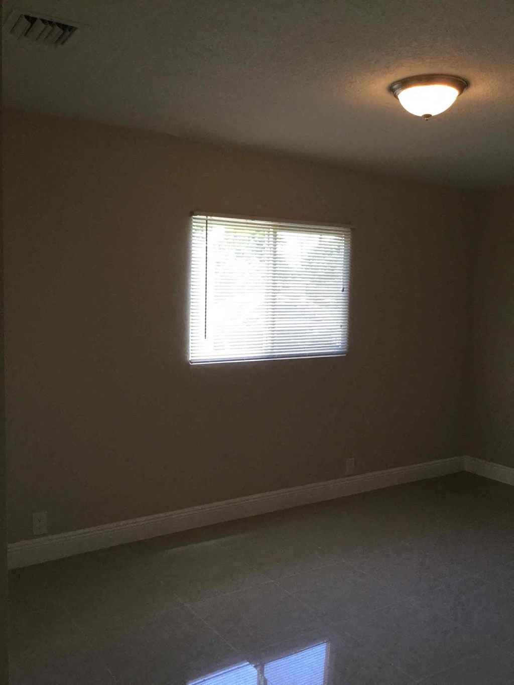 A room with a window and a ceiling light.