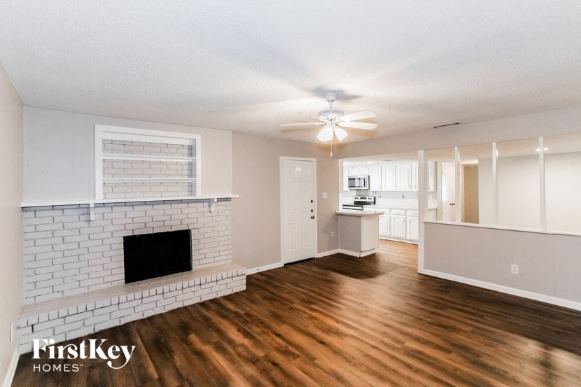 A living room with a fireplace and wooden floors.
