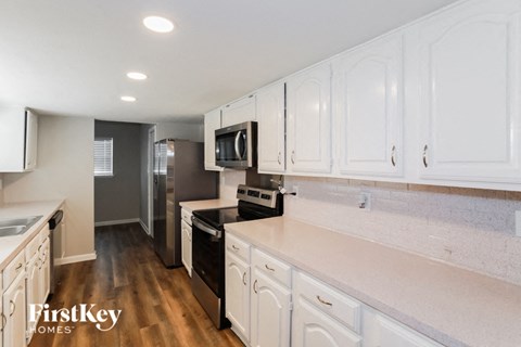 A kitchen with white cabinets and a wooden floor.