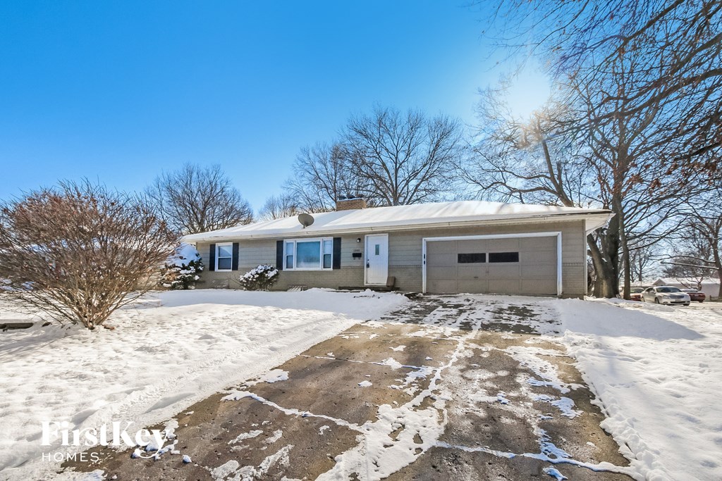 a home with snow on the driveway and a garage door