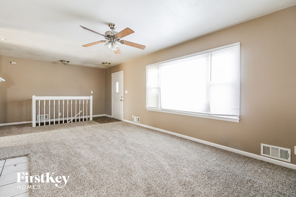 an empty bedroom with a ceiling fan and a window