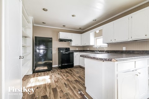 a kitchen with white cabinets and a black refrigerator
