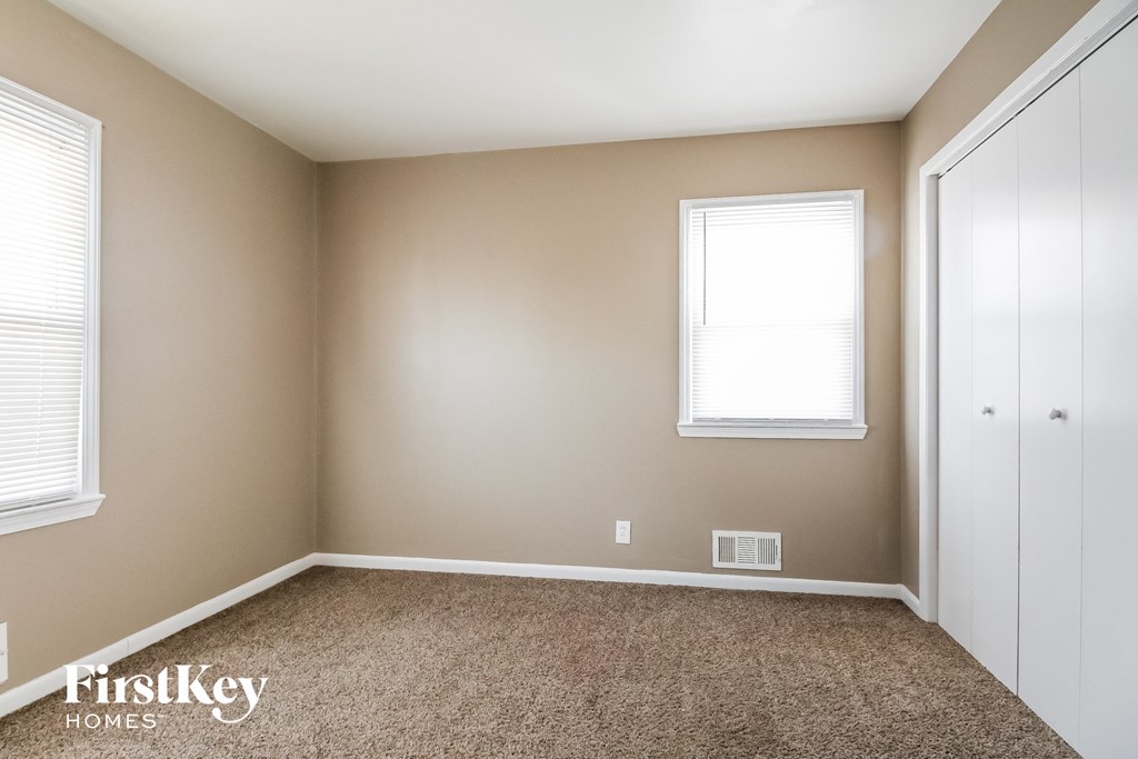 a bedroom with a carpeted floor and two windows