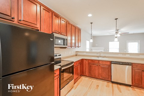 A kitchen with wooden cabinets and a black fridge.