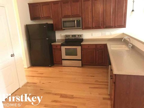 A kitchen with wooden cabinets and a black fridge.
