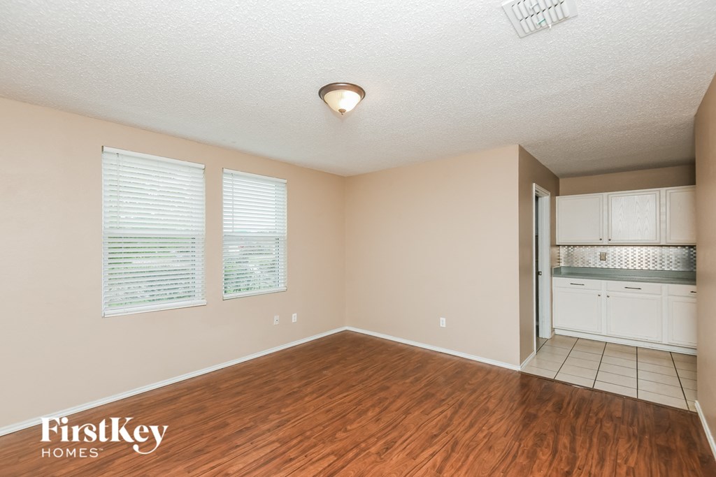 an empty living room with a hardwood floor and a kitchen