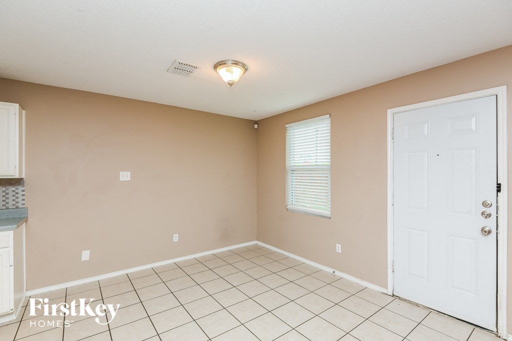 an empty living room with a white tile floor and a white door