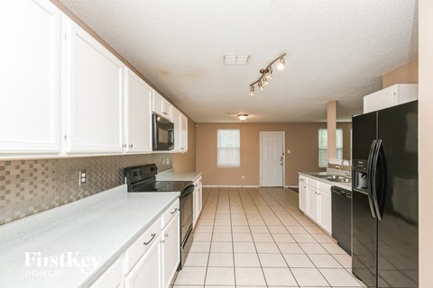 a large kitchen with white cabinets and black appliances