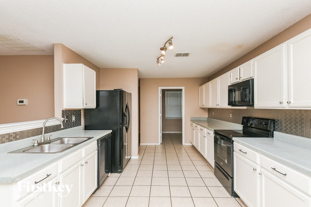 a kitchen with white cabinets and black appliances
