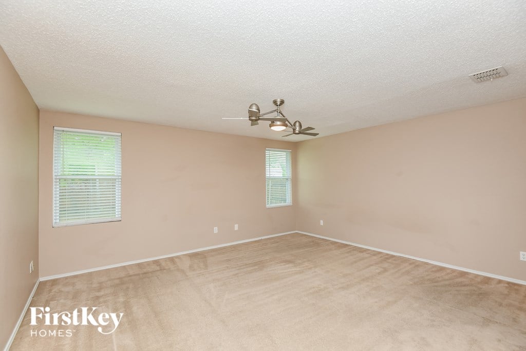 the spacious living room with beige carpeting and a ceiling fan