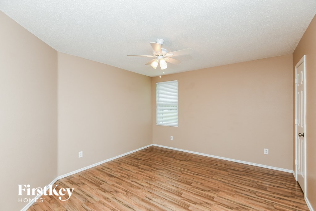 a spacious living room with hardwood floors and a ceiling fan