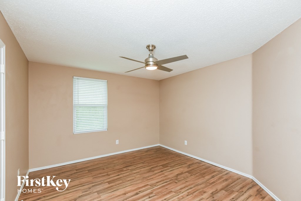 the spacious living room with hardwood flooring and a ceiling fan