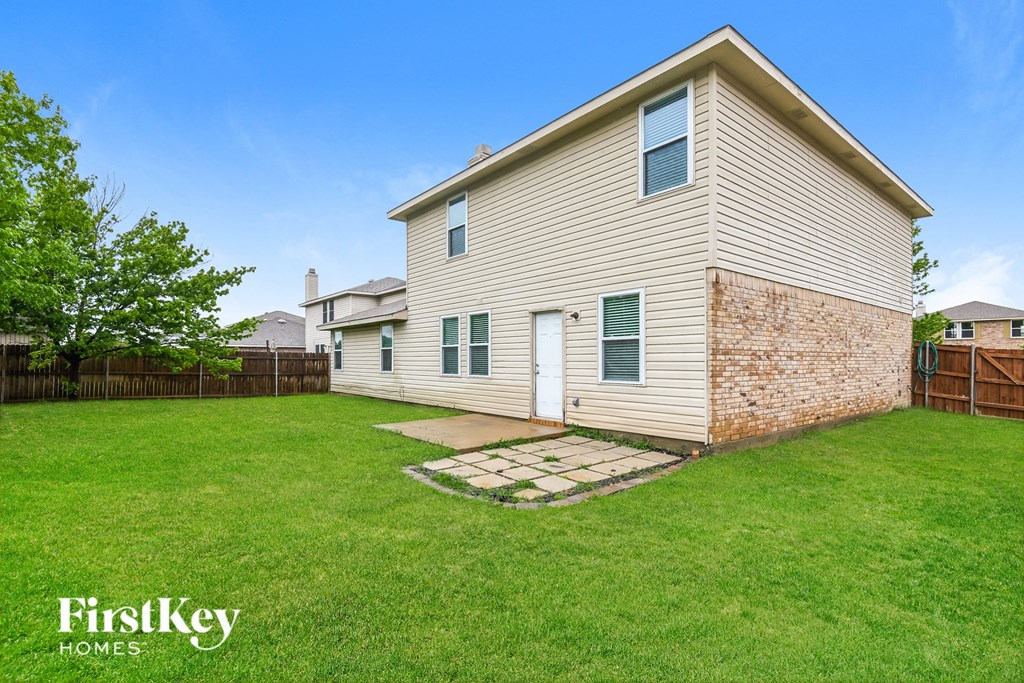 a backyard with a white house and a grassy yard