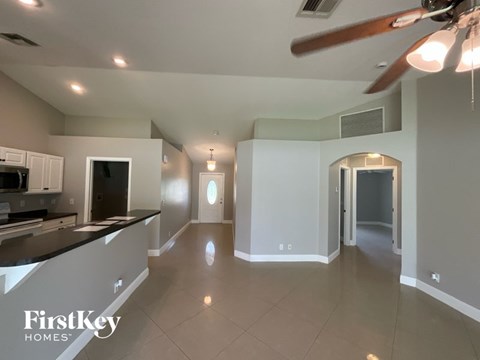 A spacious kitchen and living room with a ceiling fan and lighting fixtures.