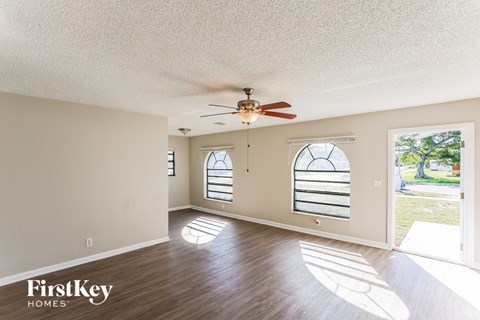 A room with a ceiling fan and two windows.