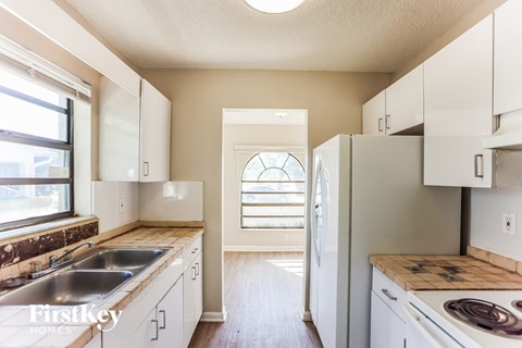 A kitchen with white cabinets and a stainless steel sink.