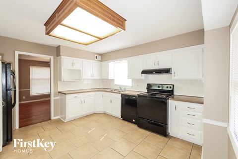 A kitchen with a black stove top oven and white cabinets.