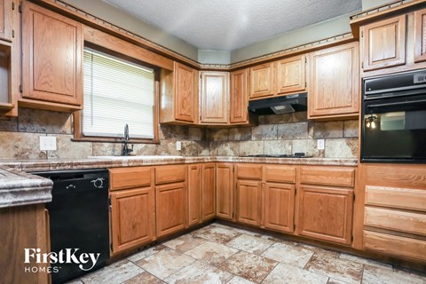 A kitchen with wooden cabinets and a black dishwasher.
