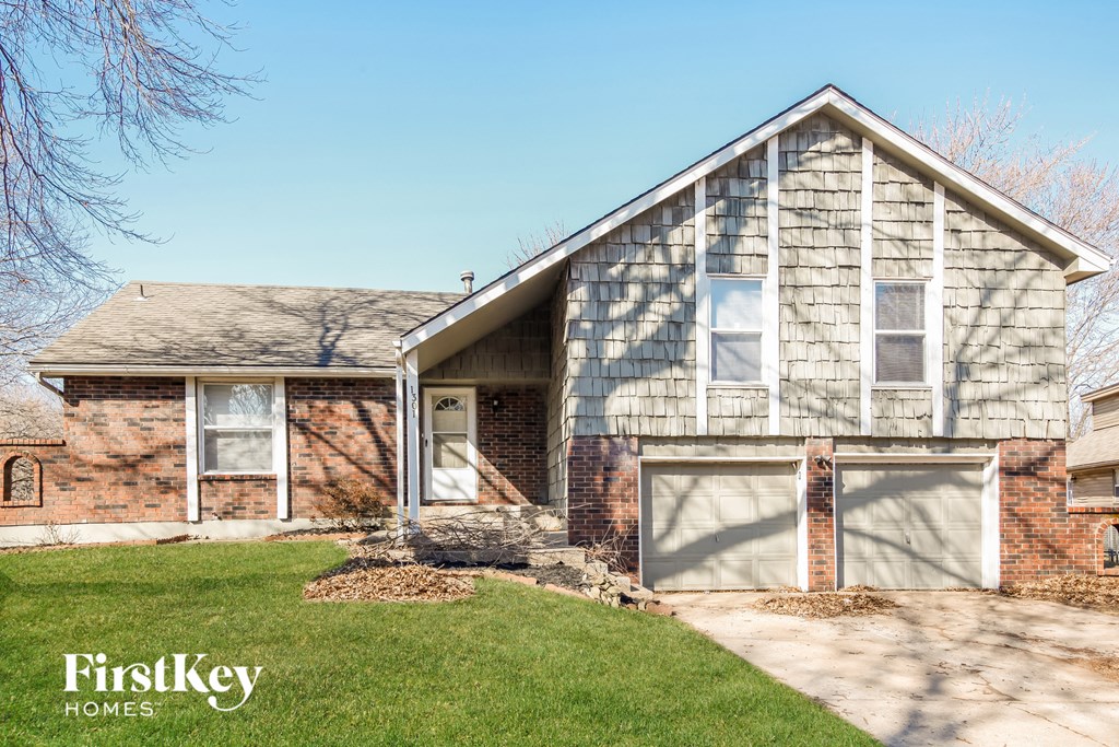 a brick house with two garage doors and a lawn