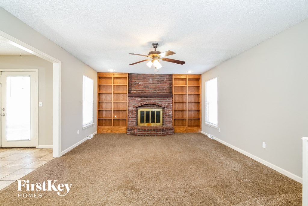 a living room with a brick fireplace and a ceiling fan