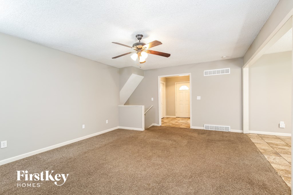 a spacious living room with carpet and a ceiling fan