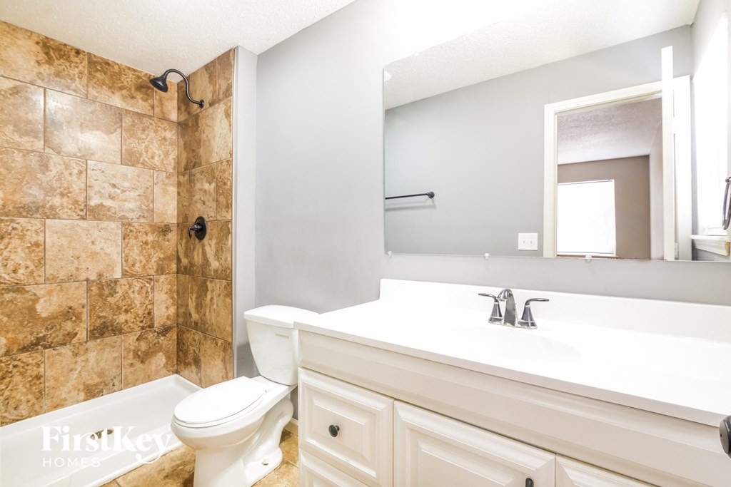 a bathroom with a sink toilet and shower and a mirror