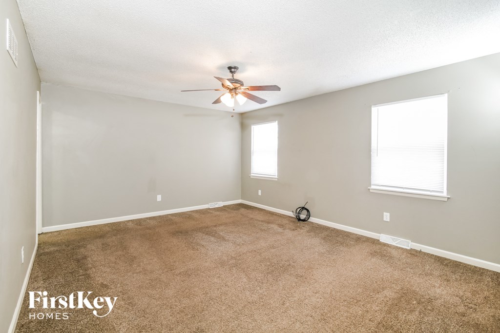 an empty living room with carpet and a ceiling fan