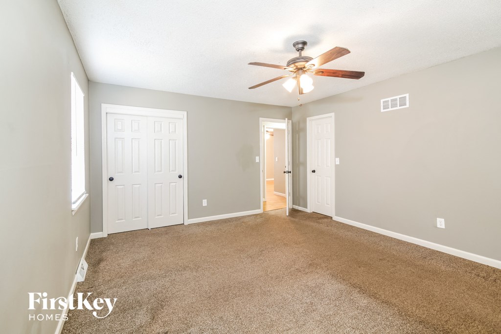 a living room with carpet and a ceiling fan