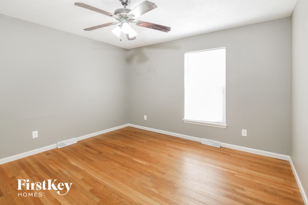 a bedroom with wood floors and a ceiling fan