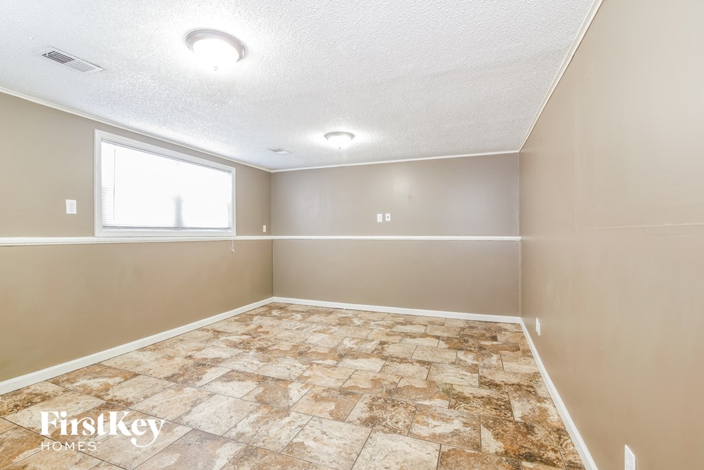 the living room of an empty house with tile floors and a window