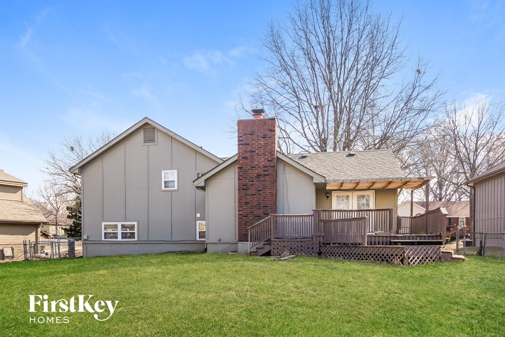 a backyard with a deck and a house with a brick chimney