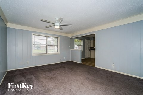 a living room with a carpet and a ceiling fan