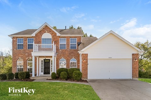 A brick house with a garage and a balcony is for sale.