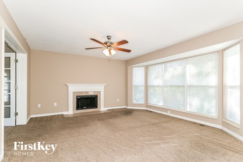 A spacious room with a fireplace and a ceiling fan.