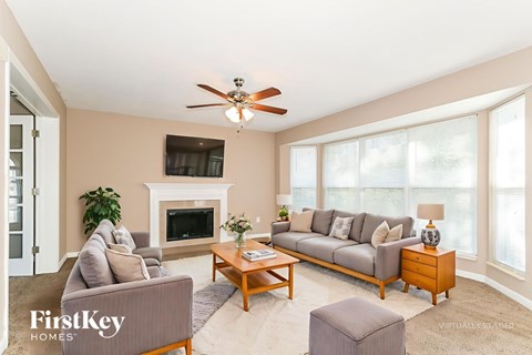 A living room with a grey couch, a coffee table, a fireplace, and a ceiling fan.