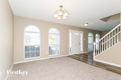 A spacious room with a staircase and a chandelier.