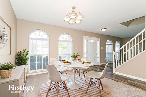 A dining room with a table set for four and a chandelier hanging from the ceiling.