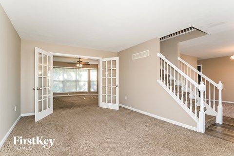 A spacious room with a staircase and a ceiling fan.