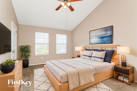 A bedroom with a large bed, a ceiling fan, and a painting on the wall.