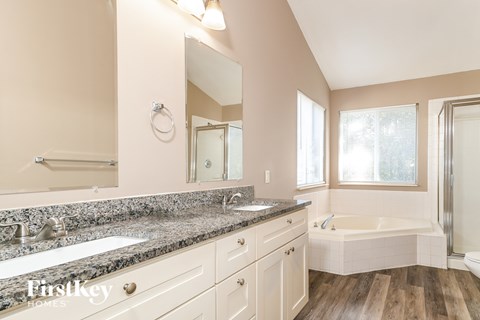 A bathroom with a tub, sink, and mirror.