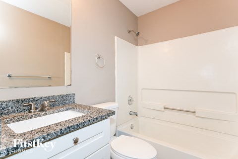 A bathroom with a granite countertop and white fixtures.